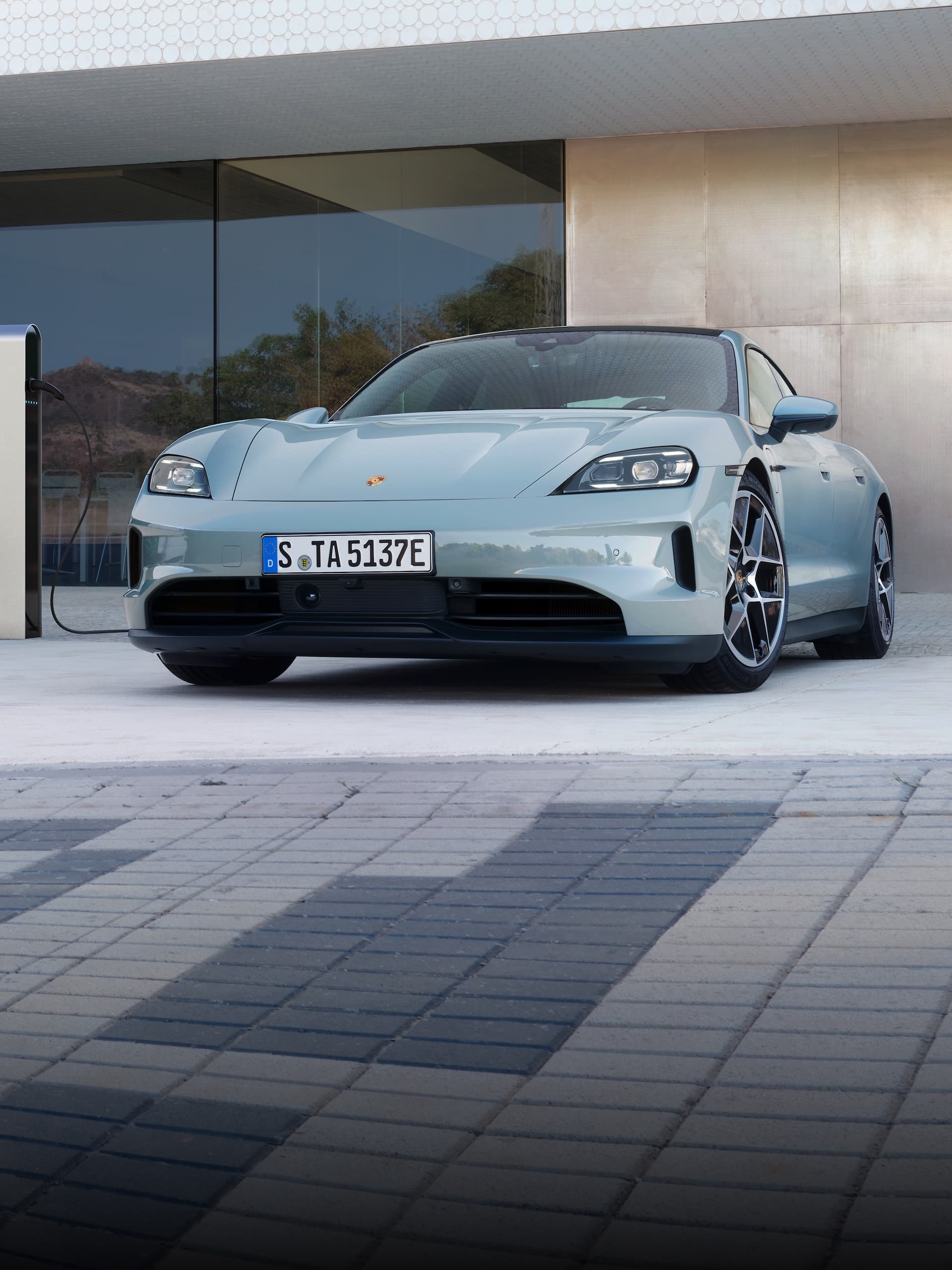 Ein Porsche Taycan parkte draussen vor einem modernen Gebäude.